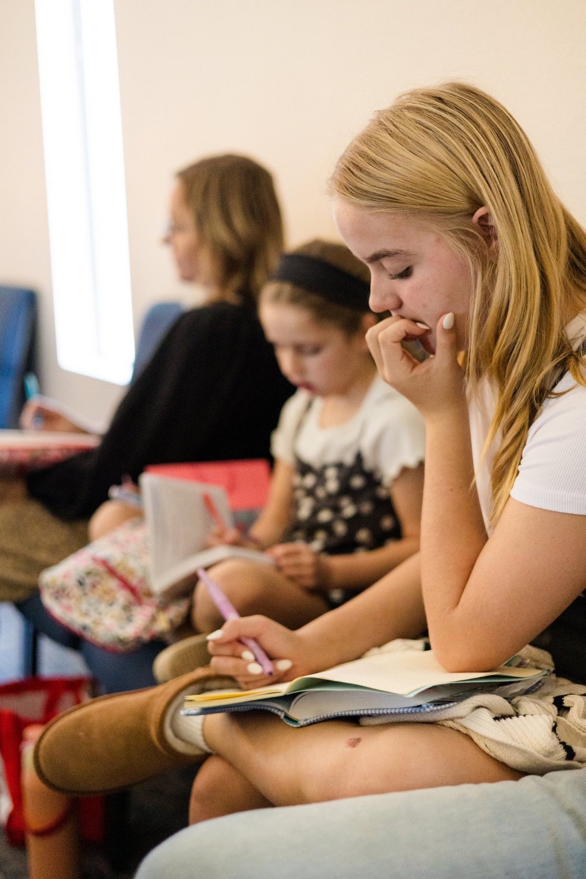 A young woman takes notes in a notebook during the sermon while others around her write too