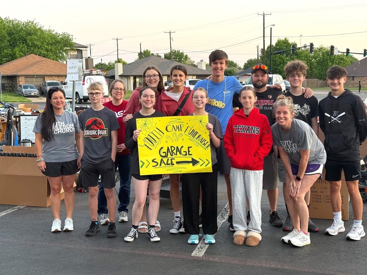 Students standing together holding a garage sale sign during a Student Ministry fundraiser